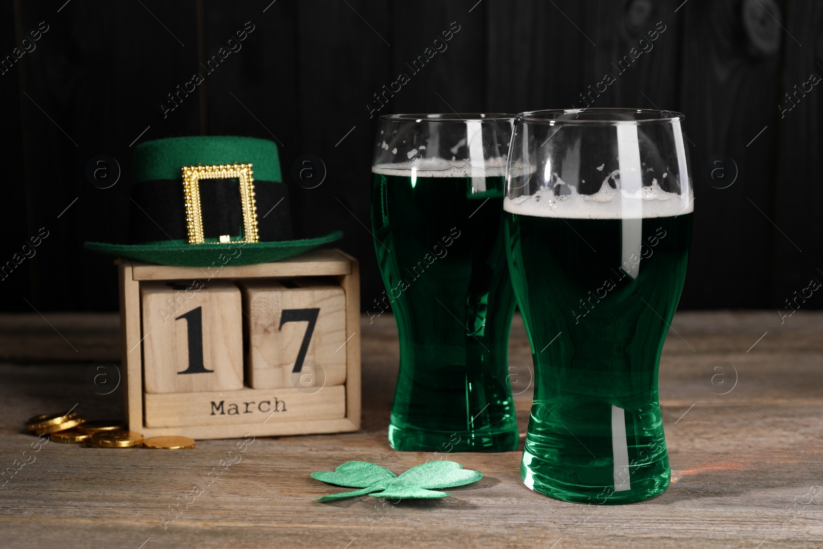 Photo of St. Patrick's day celebrating on March 17. Green beer, block calendar, leprechaun hat, gold coins and decorative clover leaf on wooden table