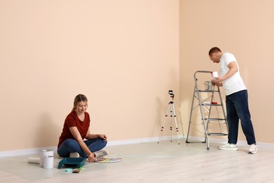 Photo of Happy couple with painting tools in apartment during repair