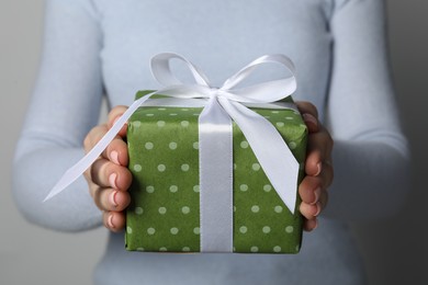 Photo of Christmas present. Woman holding gift box against grey background, closeup