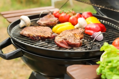 Photo of Modern grill with meat and vegetables outdoors, closeup