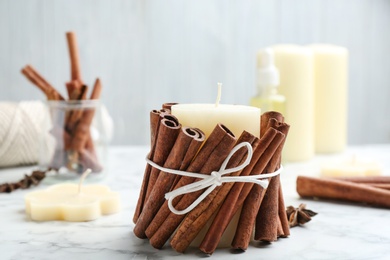 Photo of Candle with cinnamon sticks on marble table