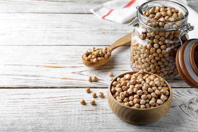 Photo of Raw chickpeas on white wooden table. Space for text