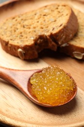 Photo of Fresh pike caviar in spoon and bread on table, closeup