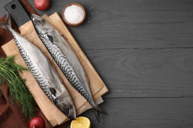 Photo of Tasty salted mackerels and products on gray wooden table, flat lay. Space for text