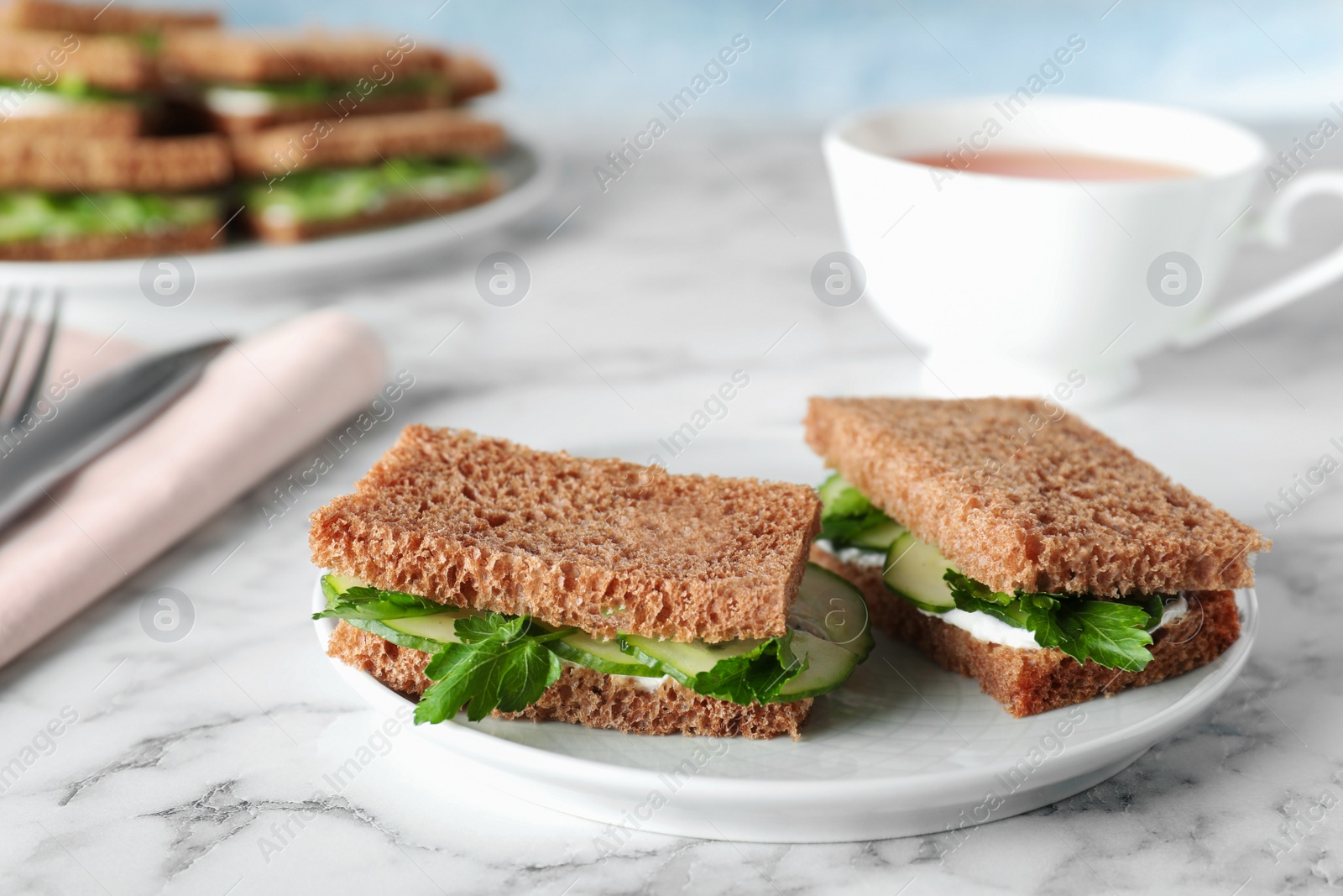 Photo of Plate with traditional English cucumber sandwiches on table