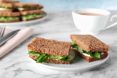 Photo of Plate with traditional English cucumber sandwiches on table