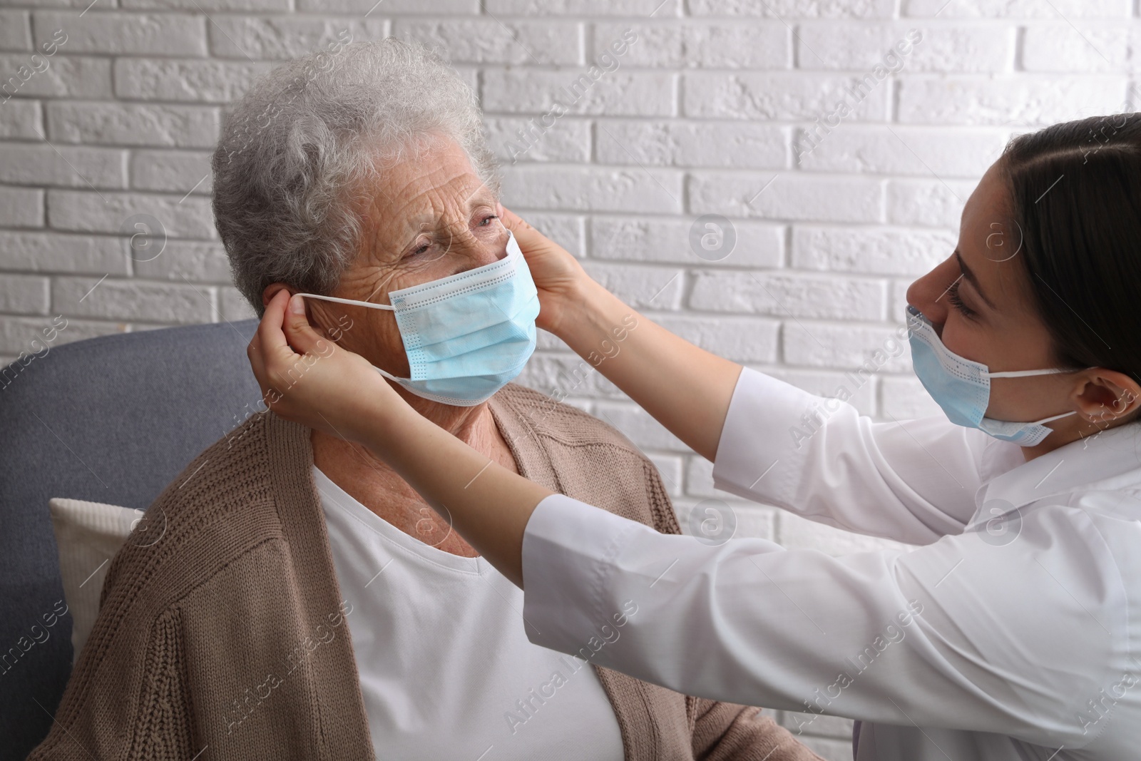 Photo of Doctor putting protective mask on senior woman at nursing home