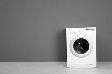 Photo of Empty washing machine near color wall, space for text. Laundry day