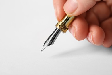 Photo of Woman with fountain pen above white paper, closeup