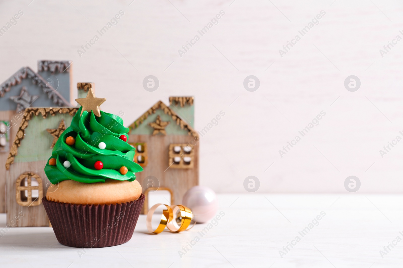 Photo of Christmas tree shaped cupcake on white table. Space for text