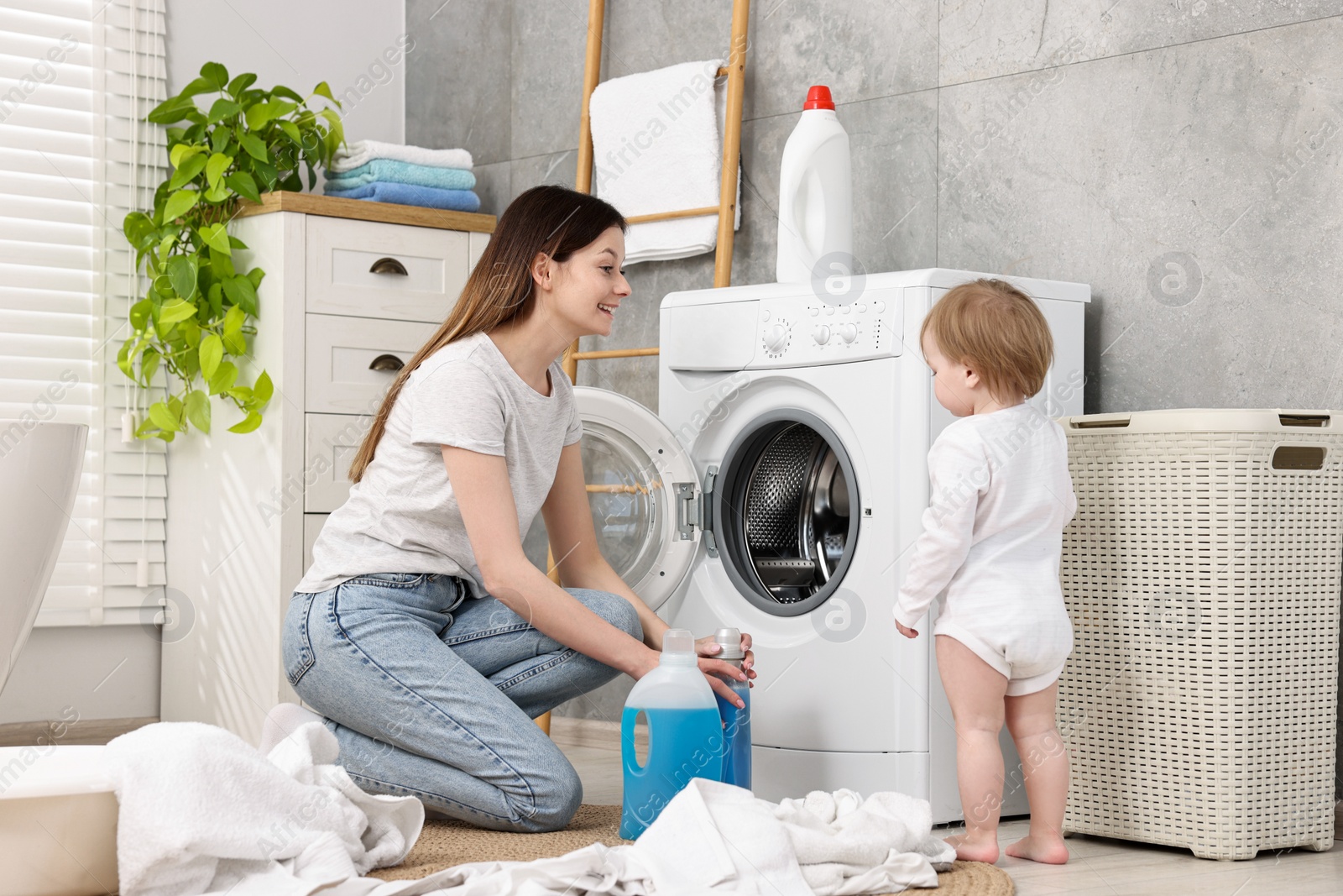 Photo of Happy mother with her daughter washing baby clothes in bathroom