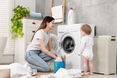 Photo of Happy mother with her daughter washing baby clothes in bathroom