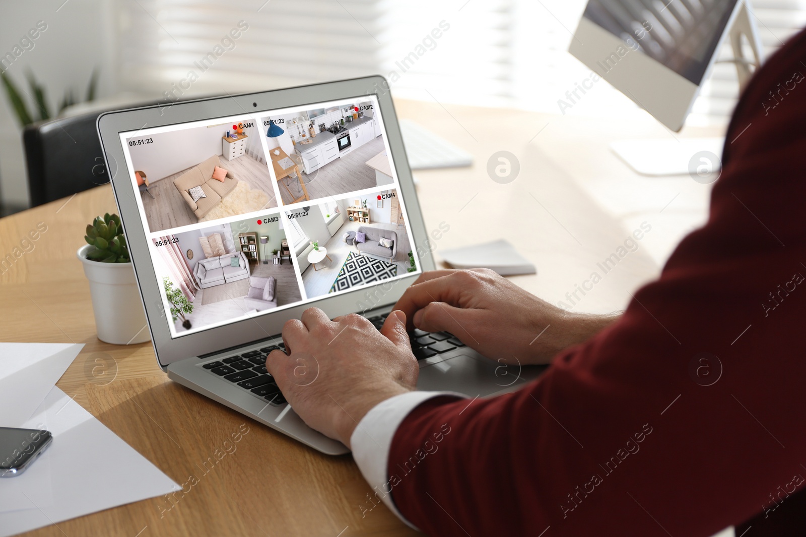 Image of Man monitoring modern CCTV cameras at wooden table, closeup. Smart home security system