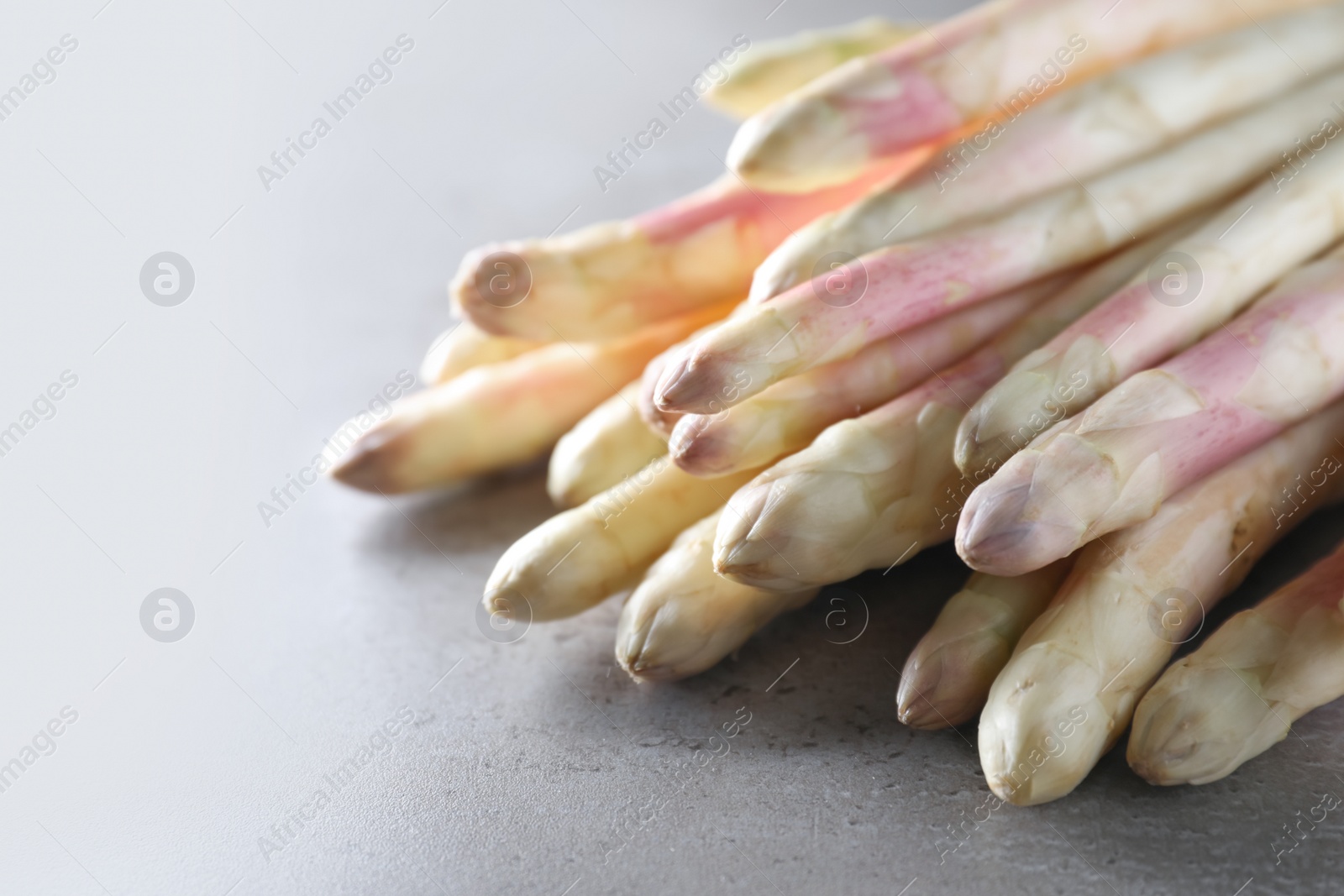 Photo of Pile of fresh white asparagus on grey table, closeup