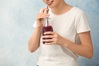 Woman with bottle of beet smoothie on light background, closeup