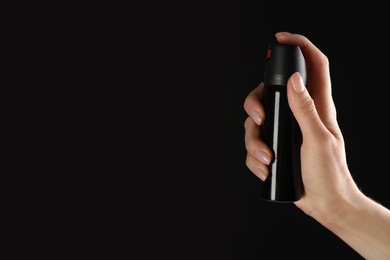 Photo of Woman holding pepper spray on black background, closeup. Space for text