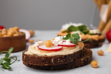 Photo of Delicious sandwiches with hummus and ingredients on light grey table, closeup