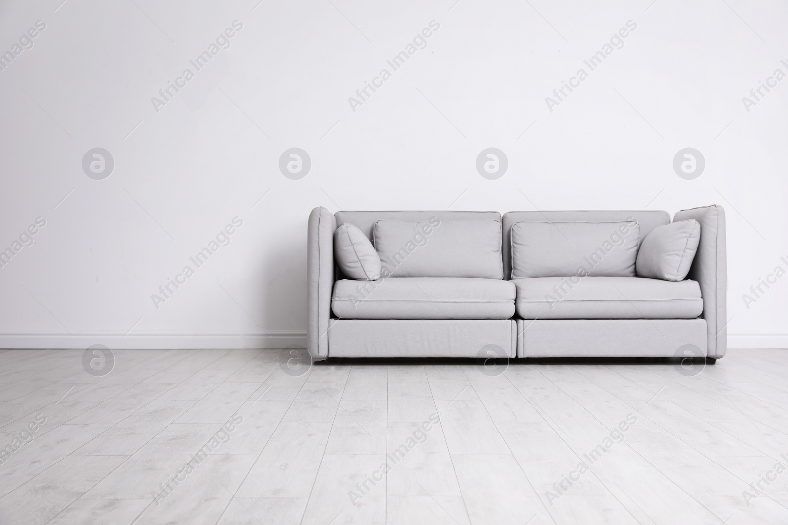 Photo of Room interior with comfortable sofa near white wall. Space for text