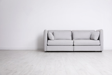 Photo of Room interior with comfortable sofa near white wall. Space for text