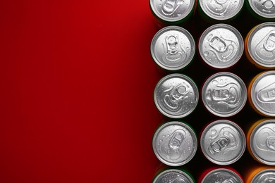 Photo of Energy drinks in wet cans on red background, top view. Space for text