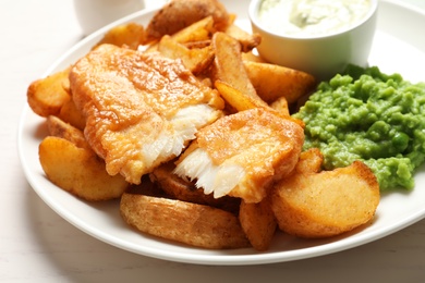 Photo of British Traditional Fish and potato chips on table, closeup