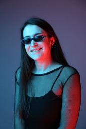 Photo of Portrait of beautiful young woman with sunglasses on color background