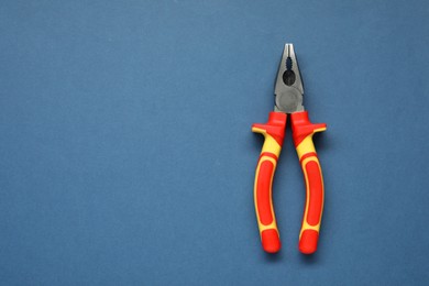 Photo of Combination pliers on blue background, top view. Space for text