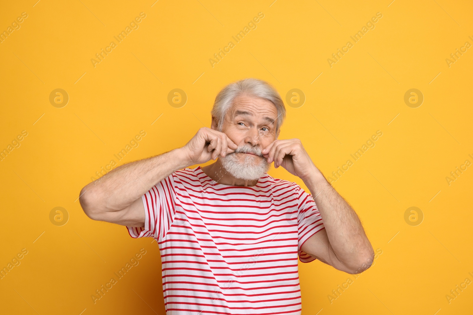 Photo of Senior man touching mustache on orange background