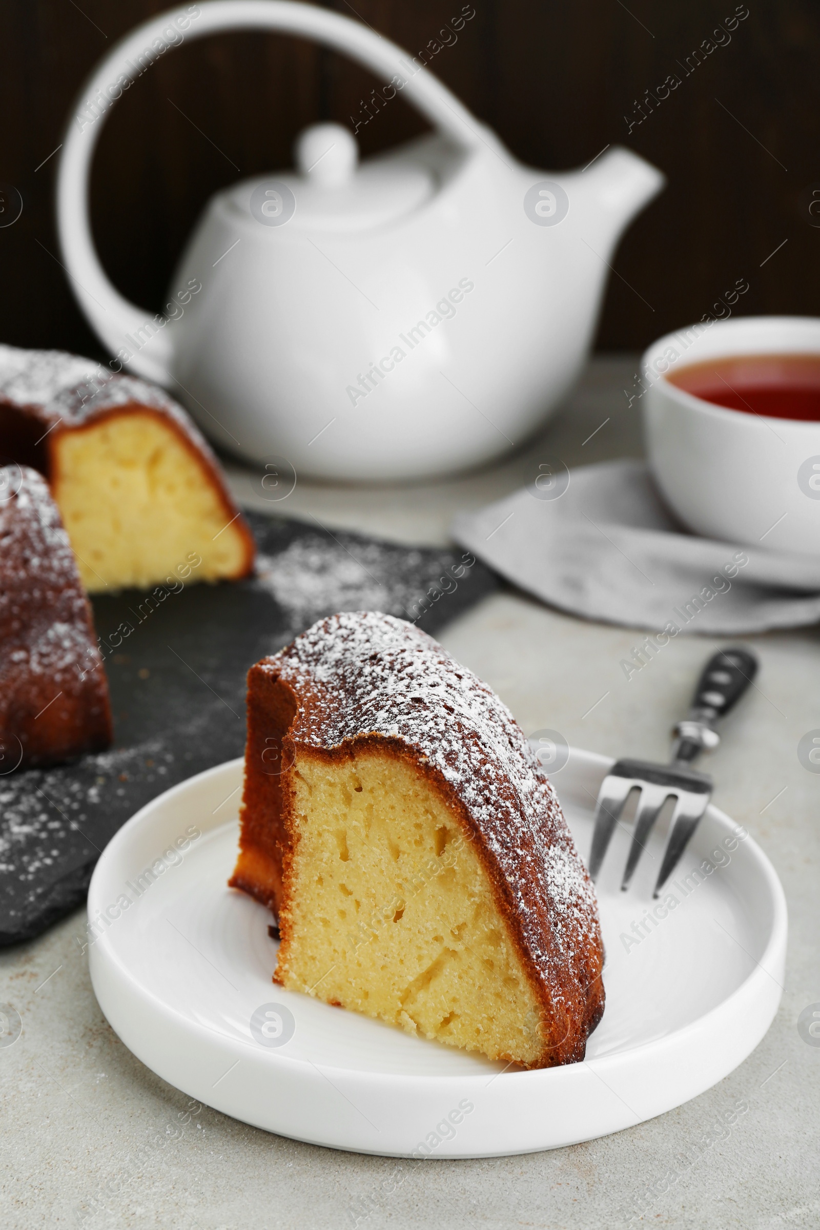 Photo of Piece of homemade yogurt cake with powdered sugar on light grey table