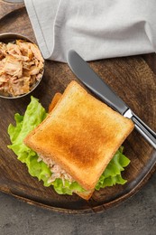 Delicious sandwich with tuna, lettuce leaves and knife on light grey table, top view