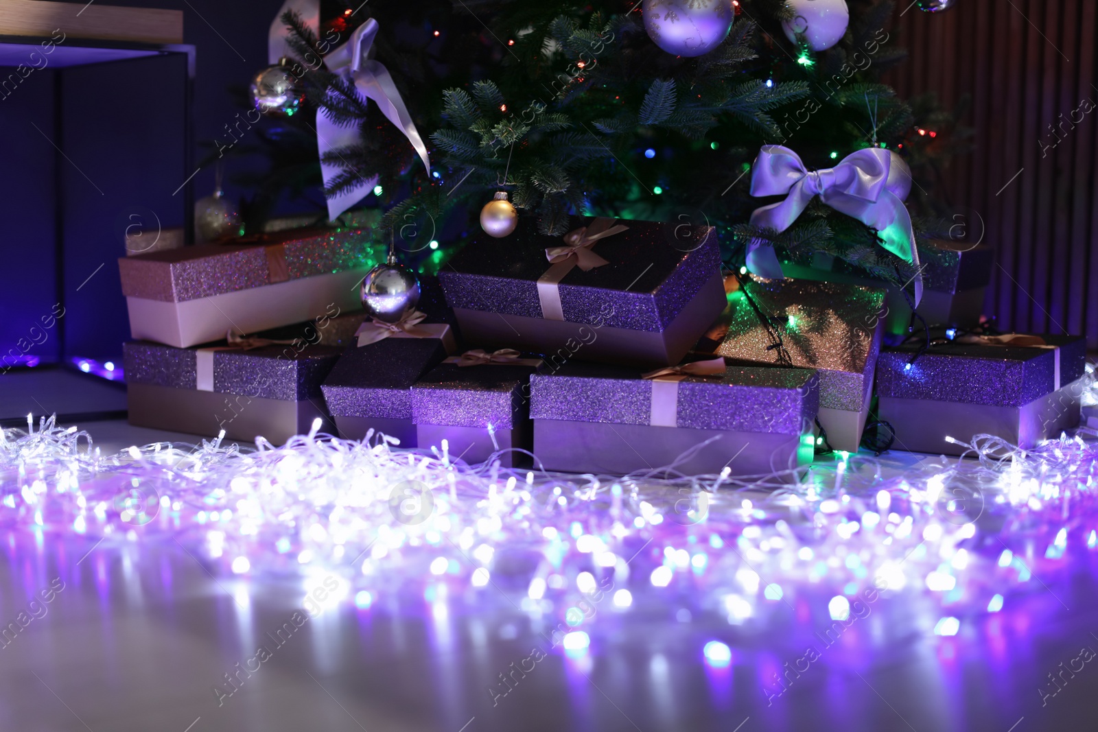 Photo of Beautiful Christmas tree, fairy lights and gift boxes indoors