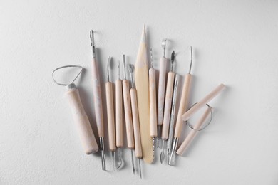 Set of different clay crafting tools on white table, top view