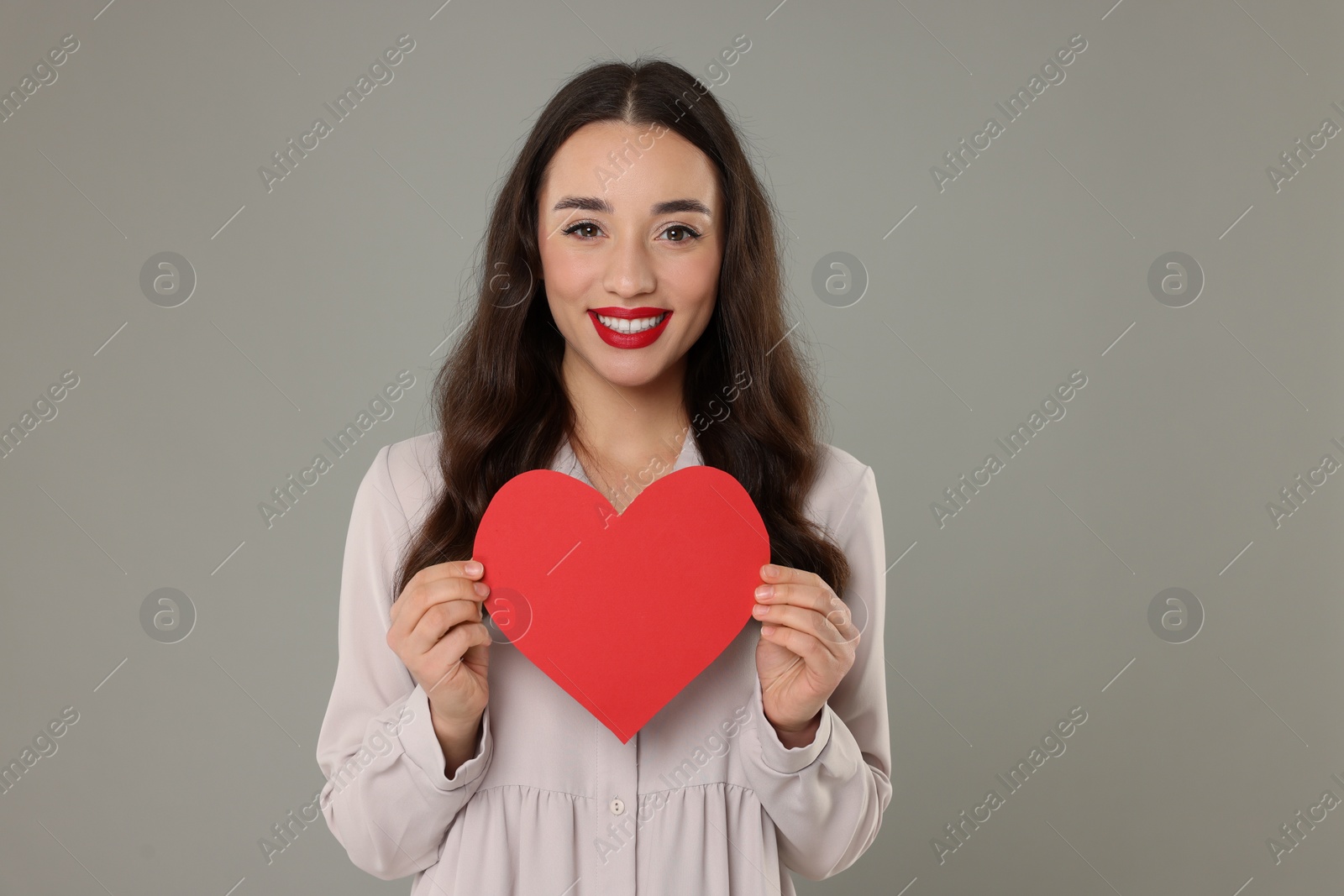 Photo of Beautiful young woman with paper heart on grey background