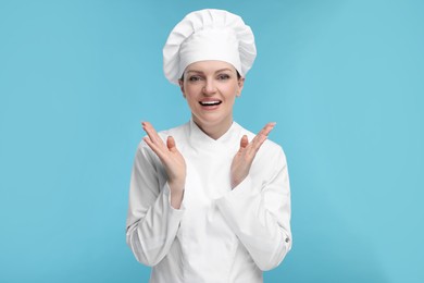 Happy chef in uniform on light blue background