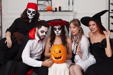 Group of people in scary costumes with carved pumpkin indoors. Halloween celebration