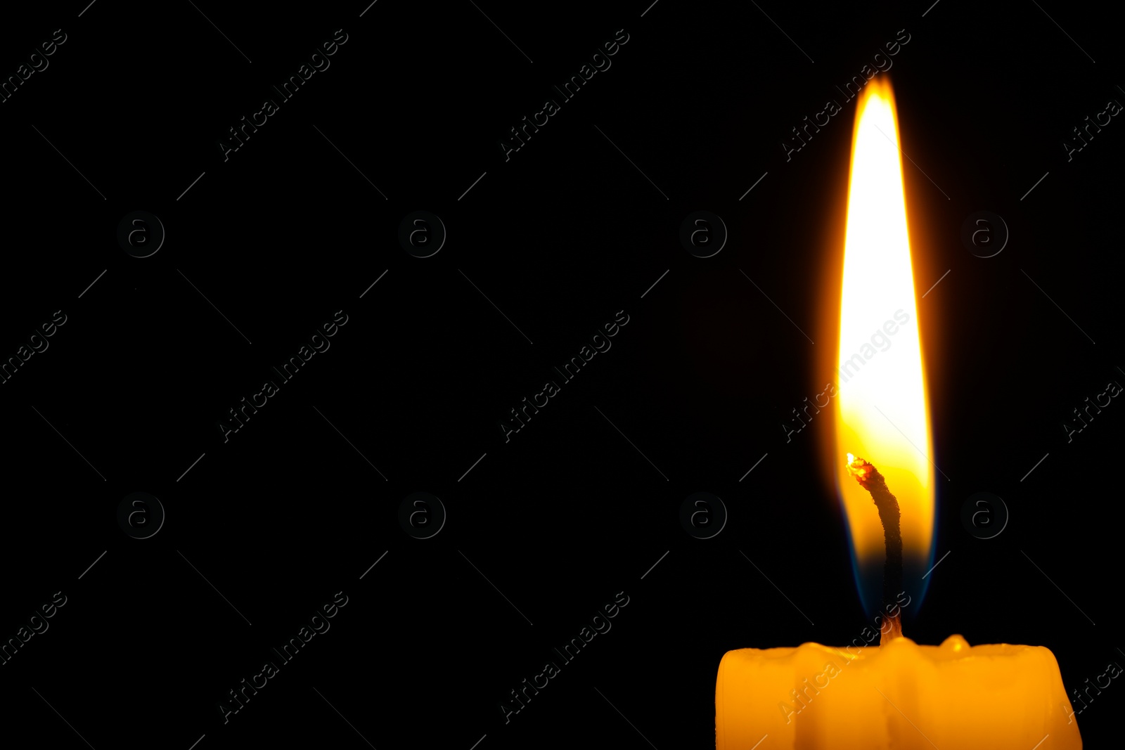 Photo of Burning candle on black background, closeup. Space for text