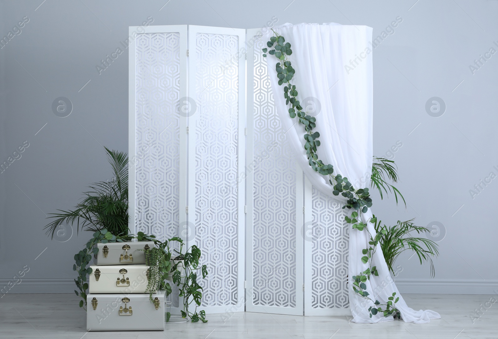 Photo of Stylish photo zone with white folding screen, floral decor and vintage suitcases indoors