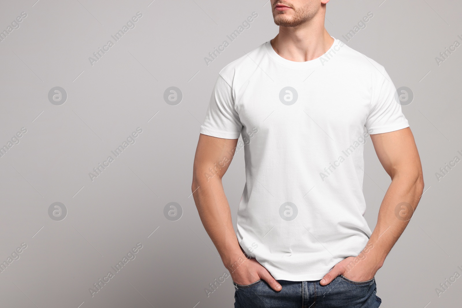 Photo of Man wearing white t-shirt on light grey background, closeup. Mockup for design