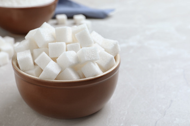 Photo of Refined sugar cubes in bowl on light grey table