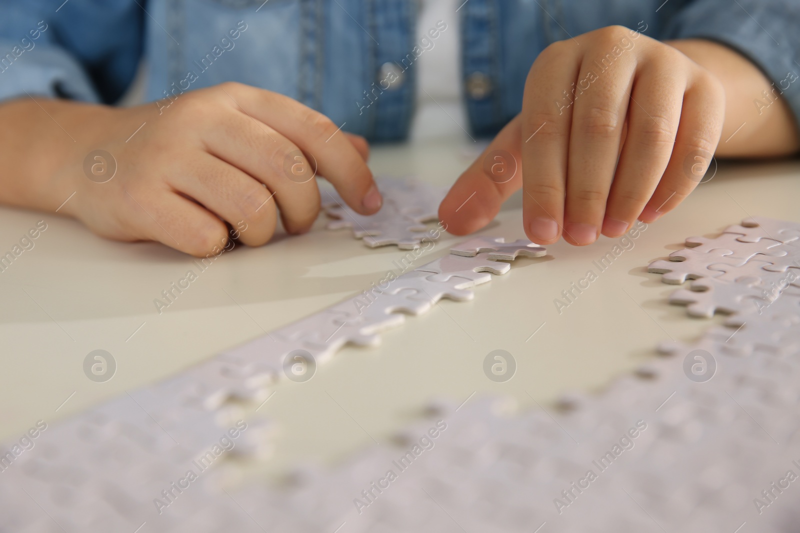 Photo of Little girl playing with puzzles at table, closeup