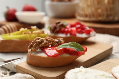 Photo of Delicious bruschettas with ricotta cheese, strawberries, walnuts and mint on table, closeup