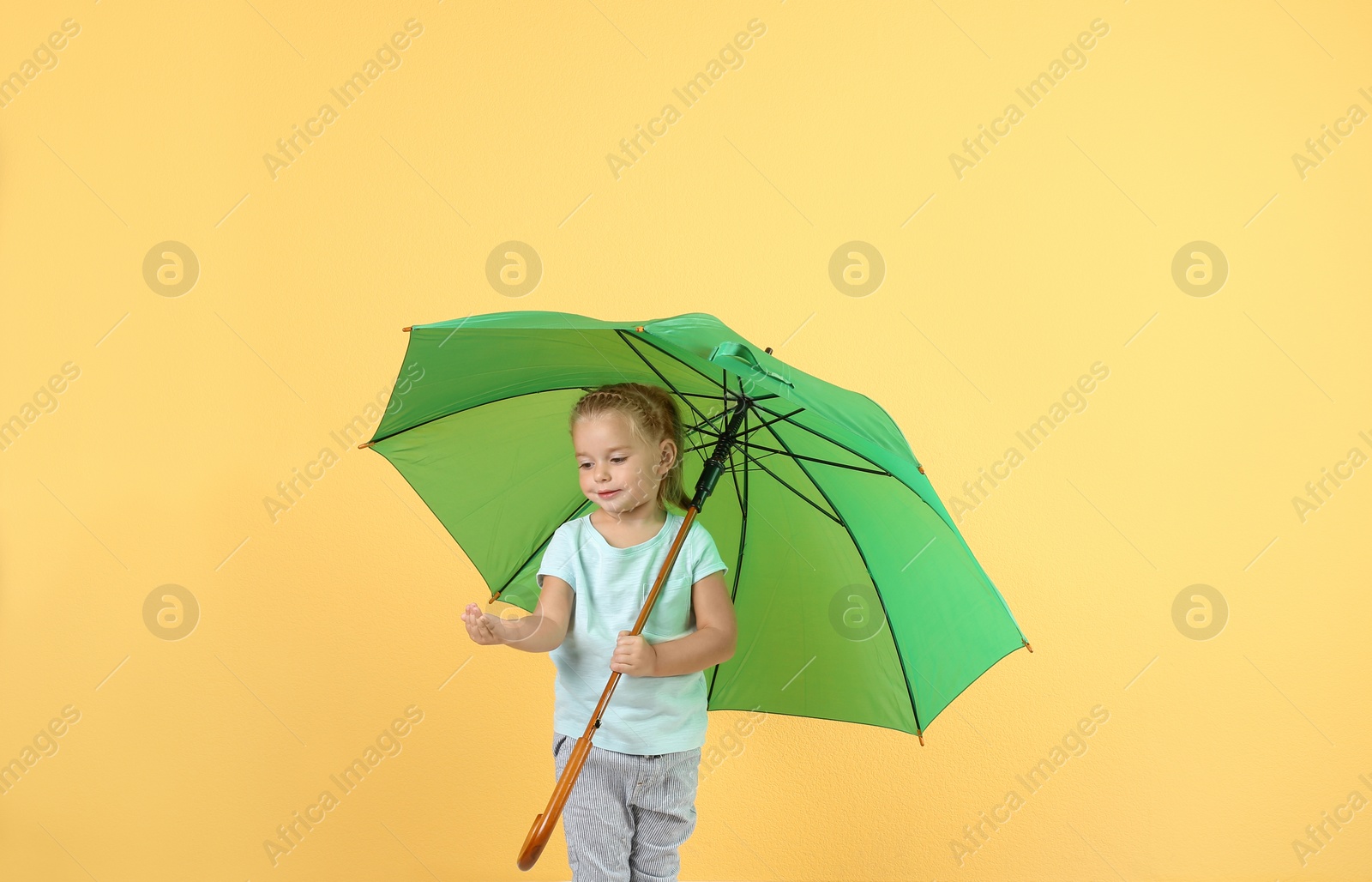 Photo of Little girl with green umbrella on color background