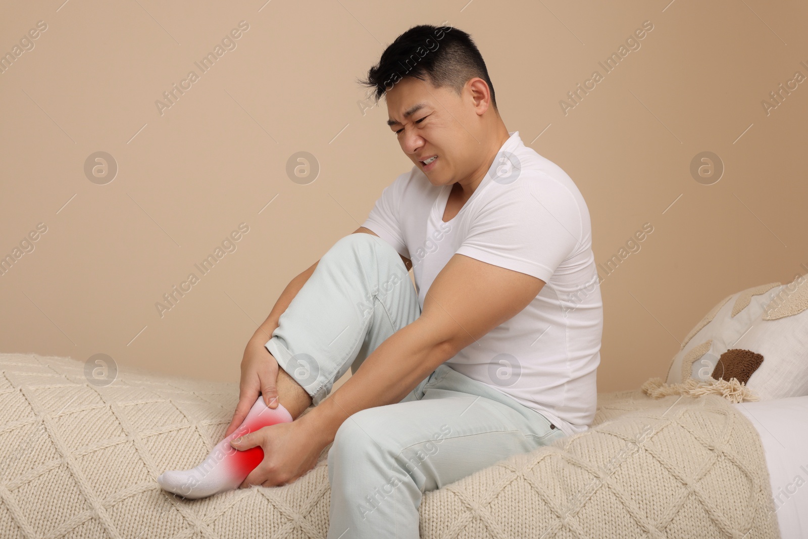 Image of Man suffering from pain in ankle on bed