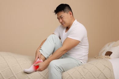 Man suffering from pain in ankle on bed