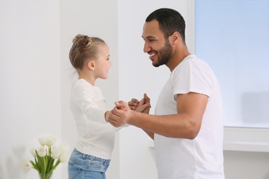 Little girl with her father spending time together at home. International family