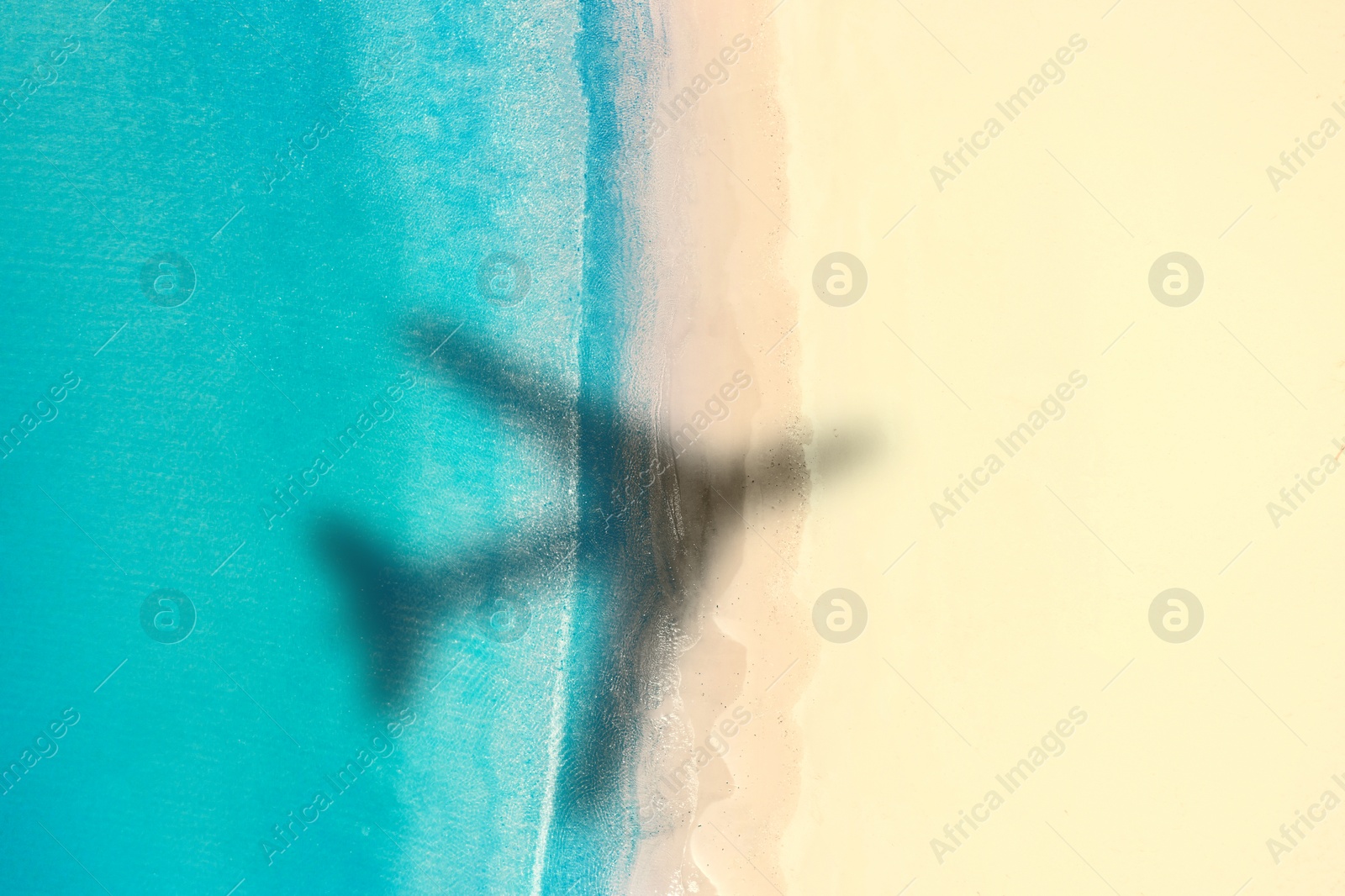 Image of Shadow of airplane above beautiful sandy beach and sea, aerial view. Summer vacation