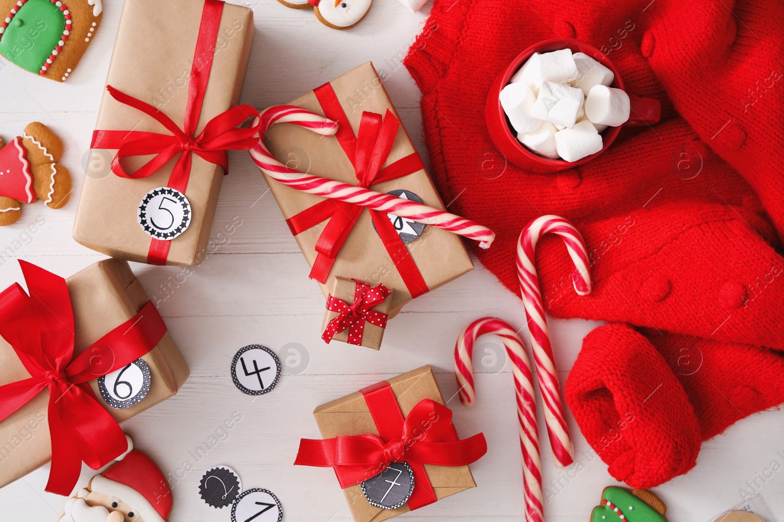 Photo of Flat lay composition with gift boxes and Christmas treats on white wooden table. Advent calendar