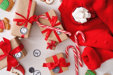 Flat lay composition with gift boxes and Christmas treats on white wooden table. Advent calendar