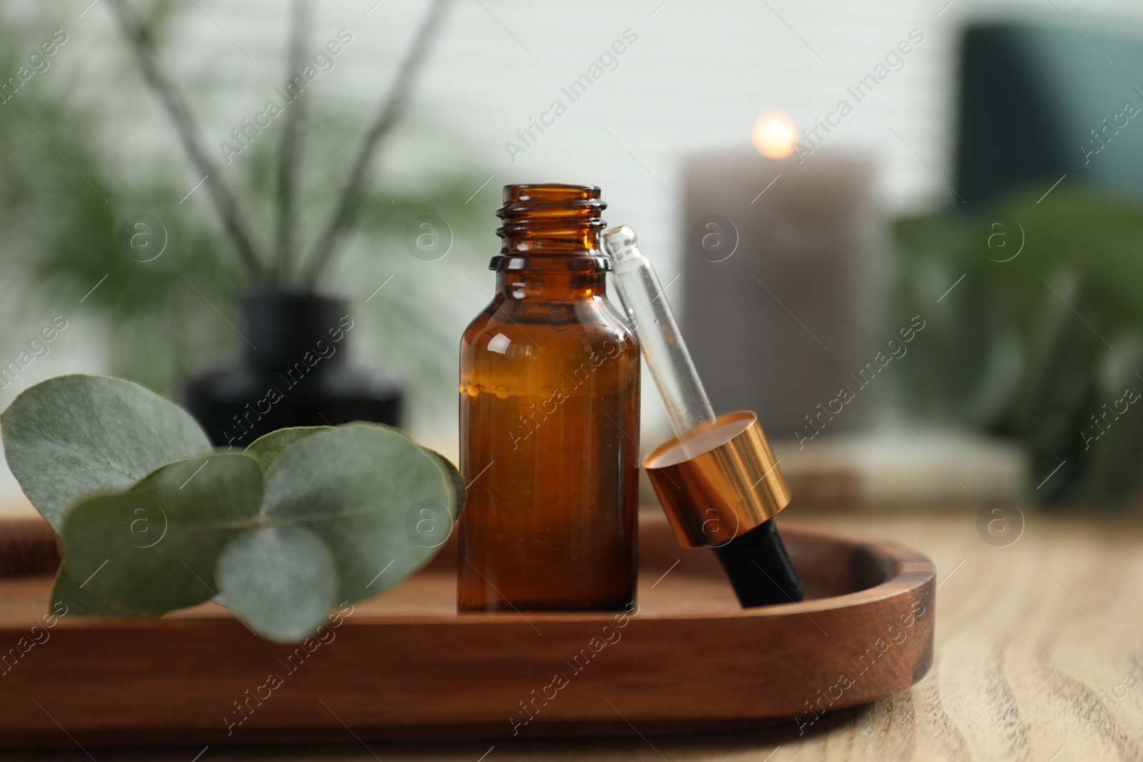 Photo of Aromatherapy. Bottle of essential oil and eucalyptus leaves on wooden table