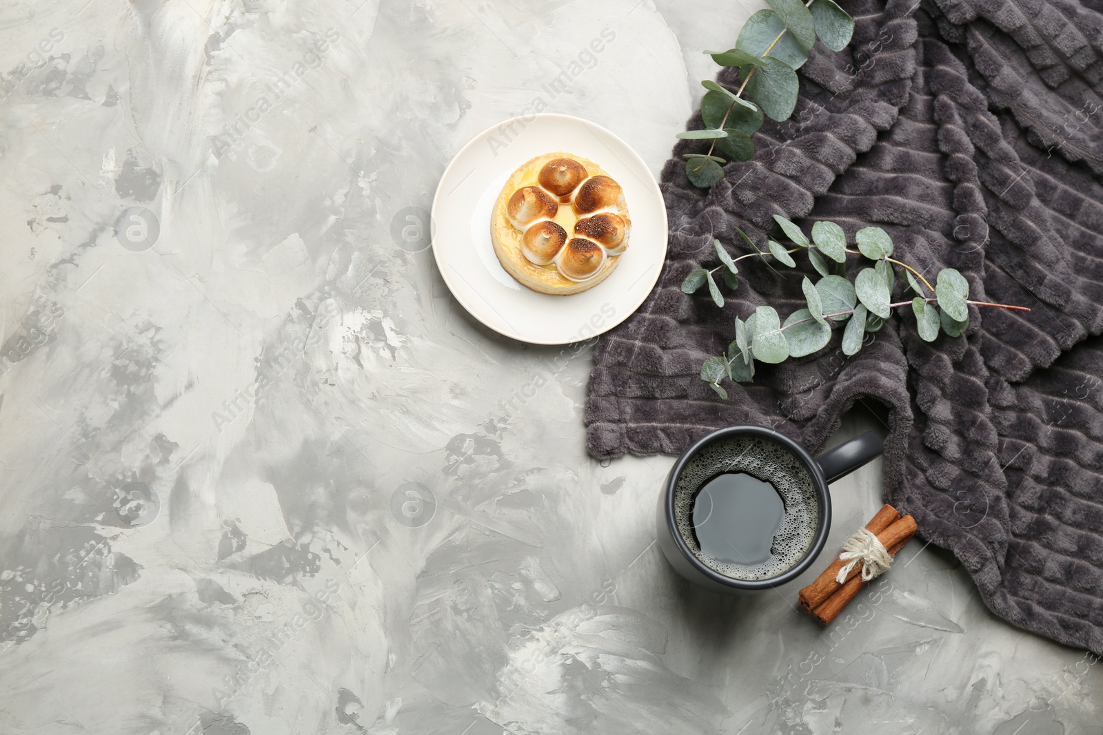 Photo of Flat lay composition with hot drink and warm plaid on grey table, space for text